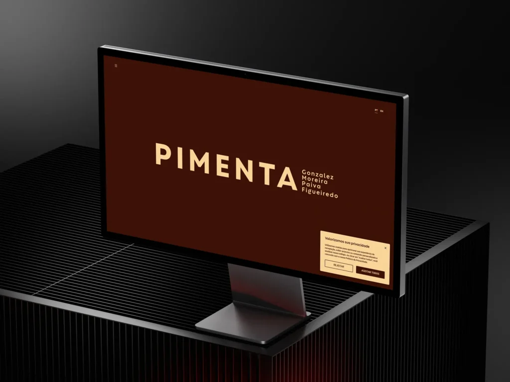 Site Pimenta Advogados exibido em monitor, com página inicial em tons de marrom e bege e destaque para o nome do escritório.